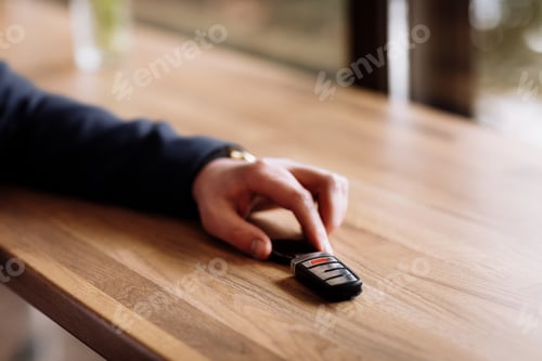 Preview: Close view of car keys put on the table by rich suited businessman in the cafe. coffee break in