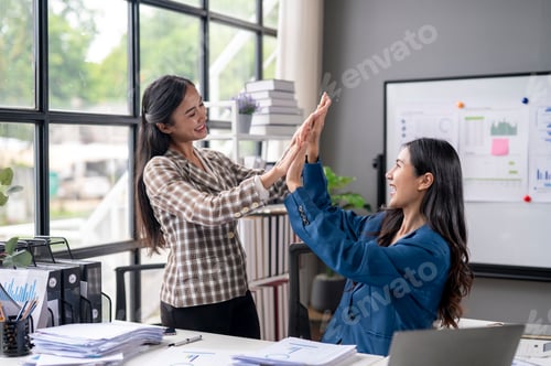 Preview: Two women are high fiving each other in a business setting