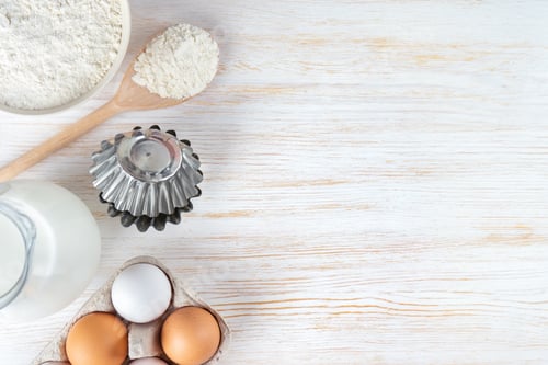 Preview: Baking Ingredients Flour, Eggs, Milk, Bakeware on White Wooden Background with Copy Space