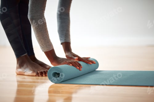 Preview: Woman Rolling Up Yoga Mat On Wooden Floor