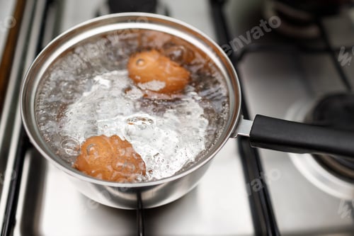 Preview: Saucepan stainless steel with boiling eggs breakfast in a water on a gas stove