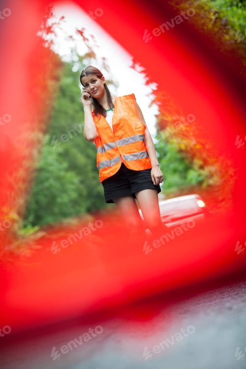 Preview: Young female driver wearing a high visibility vest, calling the