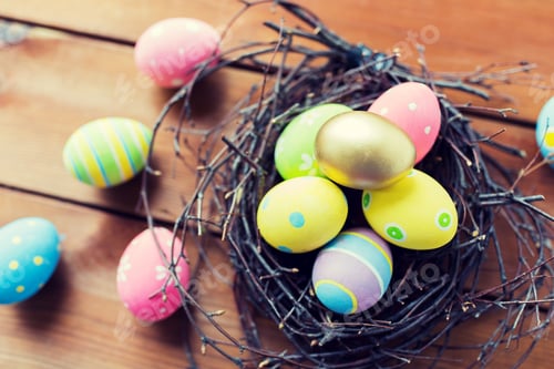 Preview: close up of colored easter eggs in nest on wood