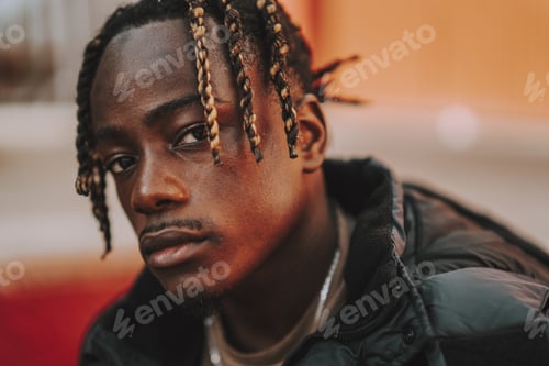 Preview: Handsome stylish Spanish man with dreads posing on a red blurred background