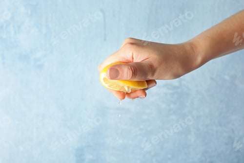 Preview: Young woman squeezing lemon on color background