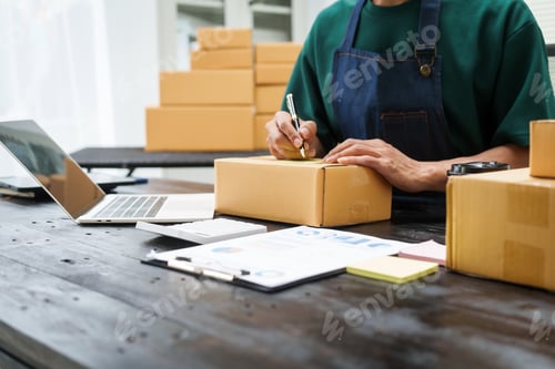 Preview: A man is working at his desk, preparing parcel boxes for shipment. He checks packs items carefully