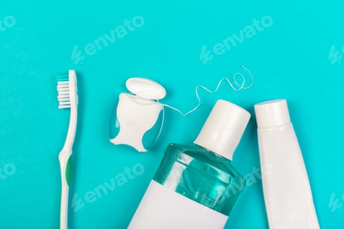 Preview: Items for dental care on a blue surface including toothbrush, toothpaste, mouthwash, and floss