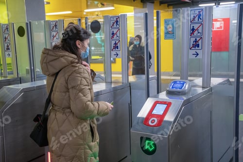 Preview: a young woman in mask scans a card at in the subway