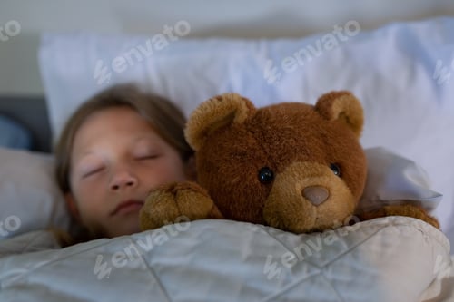 Preview: Front view of Caucasian girl sleeping on bed with teddy bear at hospital