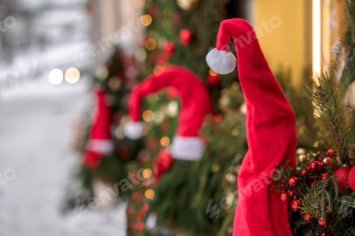 Preview: Abstract winter Christmas background with red santa hats, snow, fir branches and lights. Beautiful