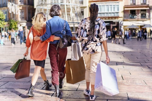 Preview: Anonymous stylish ladies walking on square with shopping bags
