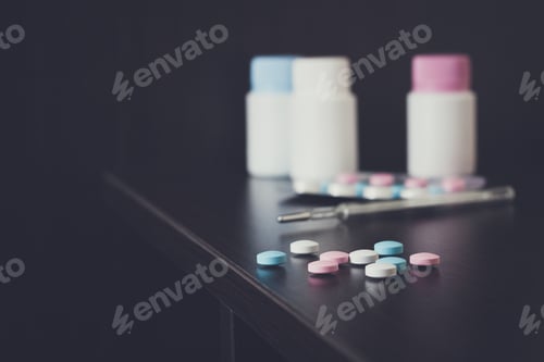 Preview: colorful pills and thermometer on brown table