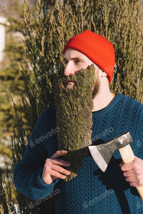 Preview: man with beard made of wood bark and axe in hand looking away outdoors