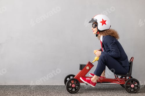 Preview: Successfull businesswoman driving toy car outdoor