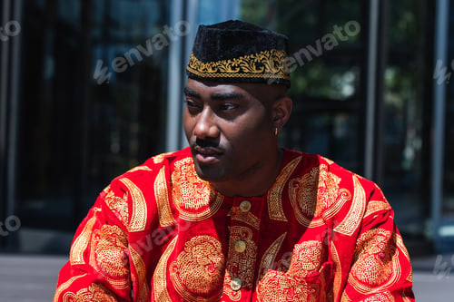 Preview: Thoughtful black man in traditional clothes and headdress near building
