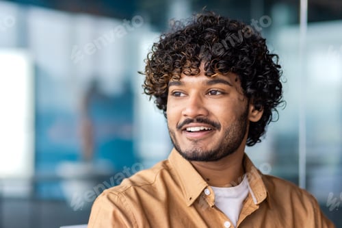 Preview: Portrait of a happy Indian man in the office, smiling widely, looking into the distance