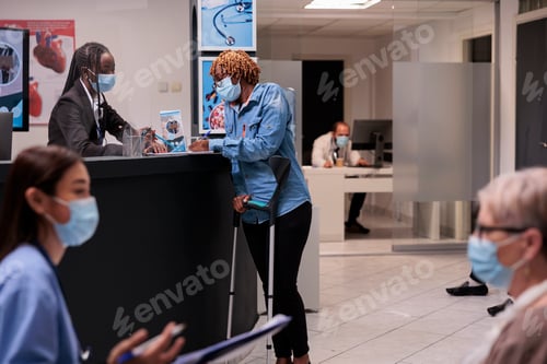 Preview: Female patient with crutches talking to receptionist