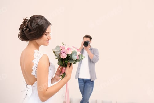 Preview: Professional photographer taking photo of beautiful bride in studio