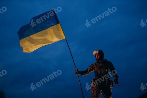 Preview: An evening photo of Ukrainian defender holding a national flag