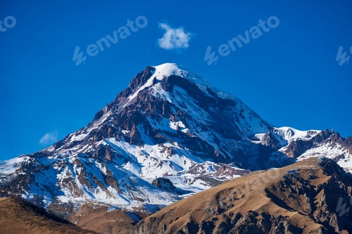 Preview: Snow-covered peaks glowing ethereally beneath a boundless blue sky.