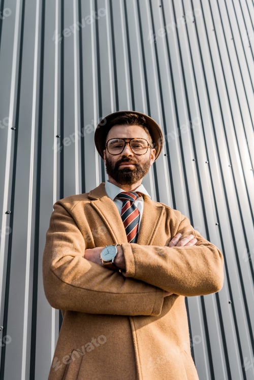 Preview: low angle view of confident businessman standing with arms crossed