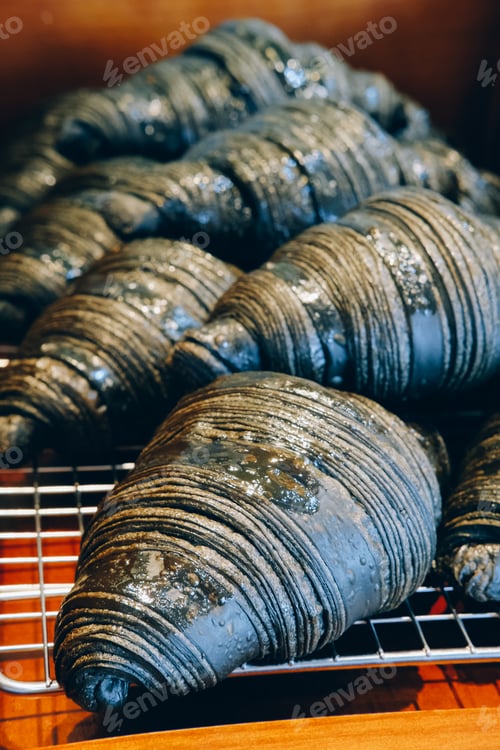 Preview: Unique charcoal croissants glistening with sugar crystals, cooling on a rack