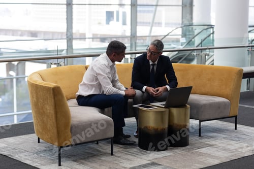 Preview: Business executives talking with each other sitting on the sofa in modern office