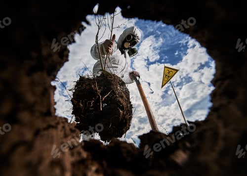 Preview: Ecologist digging pit by shovel and planting tree in polluted area.