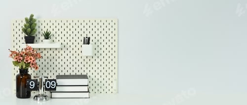 Preview: Books, vintage flip clock, and potted plants on white table against a clean white wall