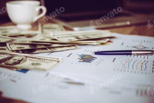 Preview: Working place of trader. The table covered by cash notes, keyboard and financial charts.