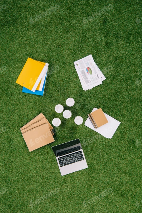 Preview: Top view of heap of business objects and office supplies laying on green grass carpet