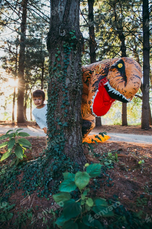 Preview: Father and son playing at the park, with a dinosaur costume, having fun with the family outdoor