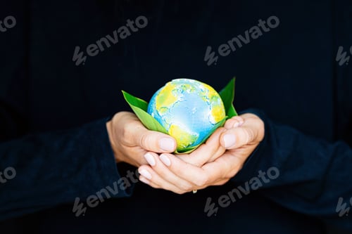 Preview: Woman Holds Globe Resting on Green Leaves