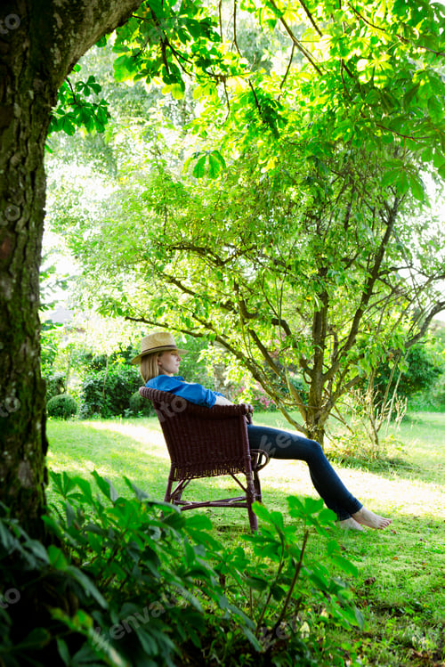 Preview: Mid adult woman asleep in garden chair
