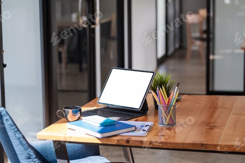 Preview: Mock up of a white screen tablet, coffee mug with documents placed on a wooden table in the office.