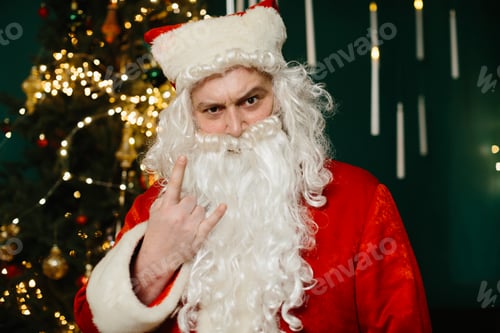 Preview: Santa claus making rock and roll hand gesture near christmas tree