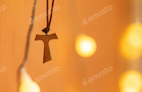 Preview: Tau cross hanging from a leather cord on a blurred background with bokeh effect