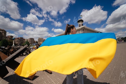 Preview: Young woman carries the flag of Ukraine fluttering behind her