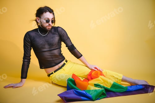 Preview: Handsome young man with pride movement LGBT Rainbow flag on shoulder against white background.