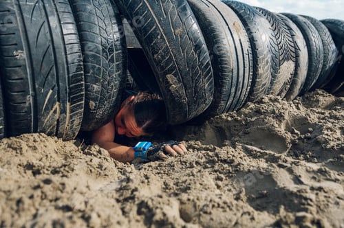 Preview: Woman crawling out of a tunnel made of car tires during an OCR race