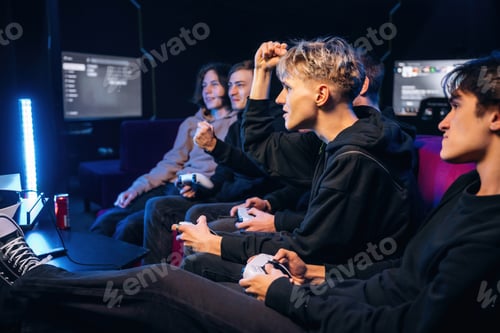 Preview: View from the side, sitting. Group of young gamers are indoors
