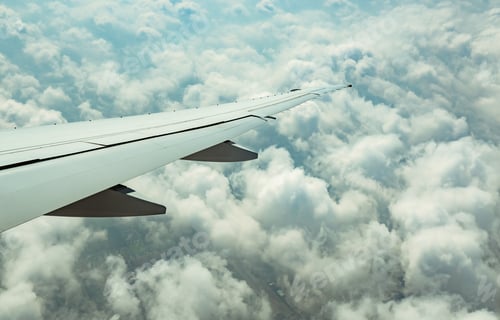 Preview: Wing of plane over white clouds. Airplane flying on blue sky. Scenic view from airplane window.