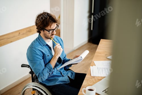 Preview: Young disabled entrepreneur analyzing business plans while working at home.