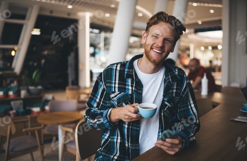 Preview: Guy using smartphone and drinking tea in office
