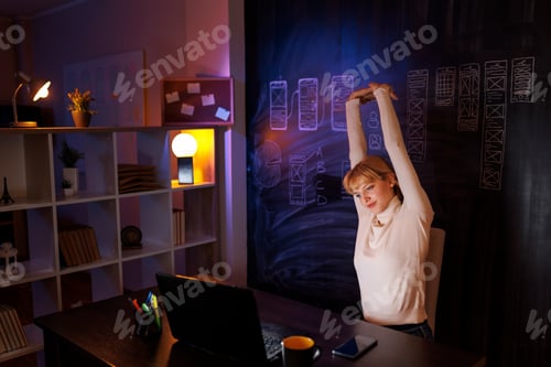 Preview: Female UX UI designer stretching while working overtime