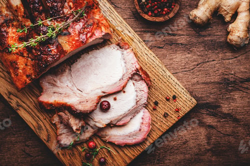 Preview: Baked pork loin on rustic wooden cutting board with spices, herbs and cranberries