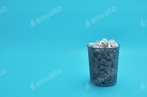 Preview: Metal bin with crumpled paper on color background, space for text