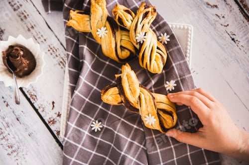 Preview: Kids hand taking delicious Palmiers with chocolate on wooden background