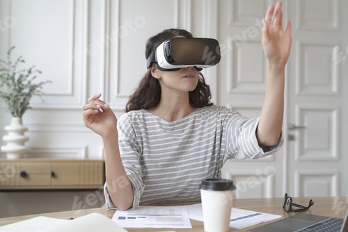 Preview: Concentrated woman bank accountant in VR headset sitting at desk at home office