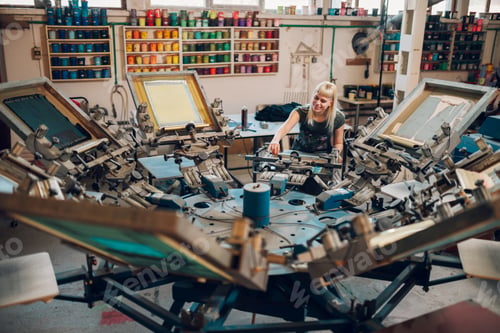 Preview: Printing shop worker adjusting screen carousel printing machine for work